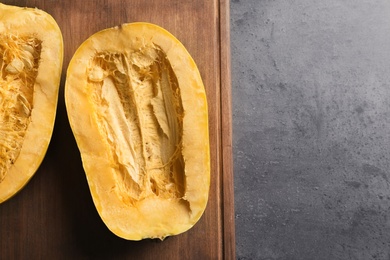 Photo of Wooden board with cut spaghetti squash on gray background, top view. Space for text
