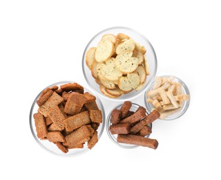 Different crispy rusks in bowls on white background, top view