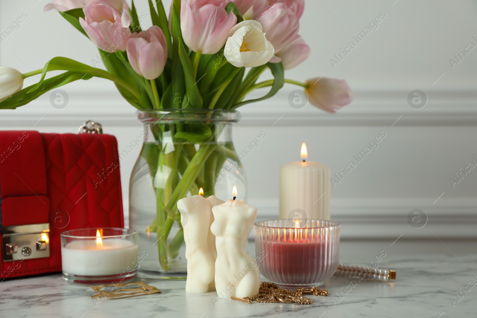 Photo of Beautiful female and male body shaped candles on white marble table. Stylish decor