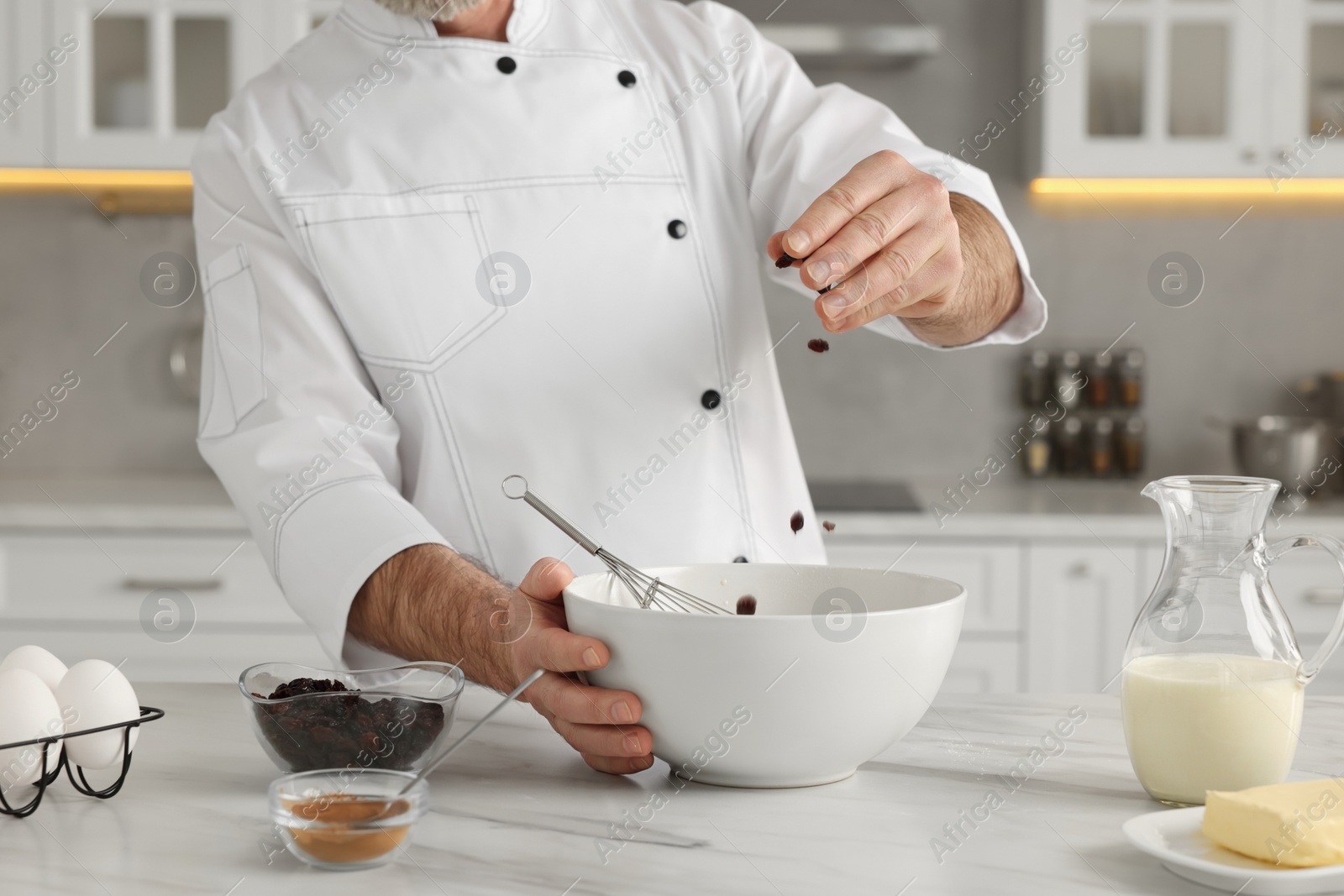 Photo of Professional chef making dough at white marble table indoors, closeup