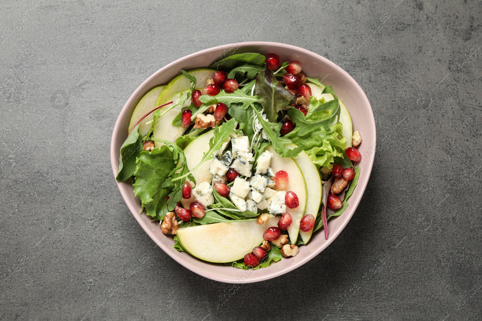 Photo of Tasty salad with pear slices and pomegranate seeds on grey table, top view