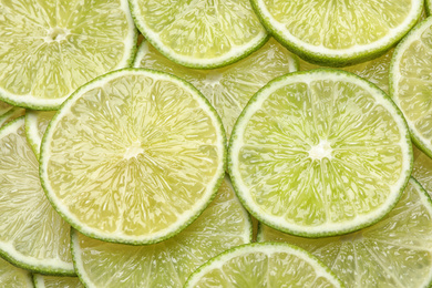 Many fresh juicy lime slices as background, top view