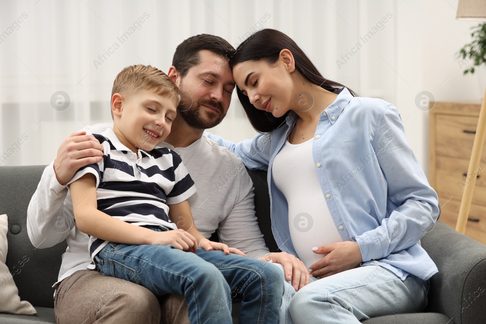 Photo of Pregnant woman spending time with her son and husband at home