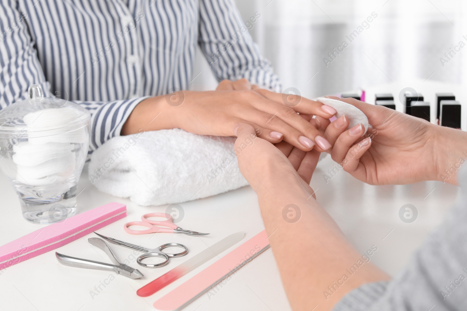 Photo of Manicurist removing polish from client's nails in salon, closeup