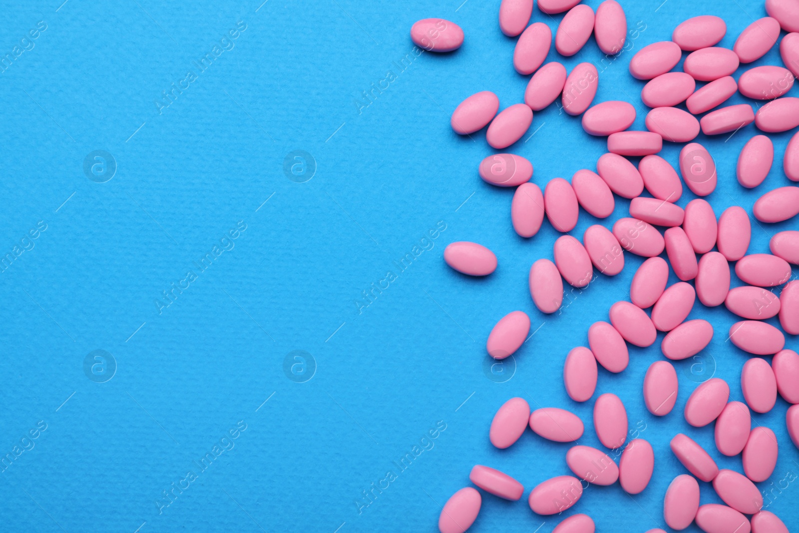 Photo of Many pink dragee candies on blue background, flat lay. Space for text