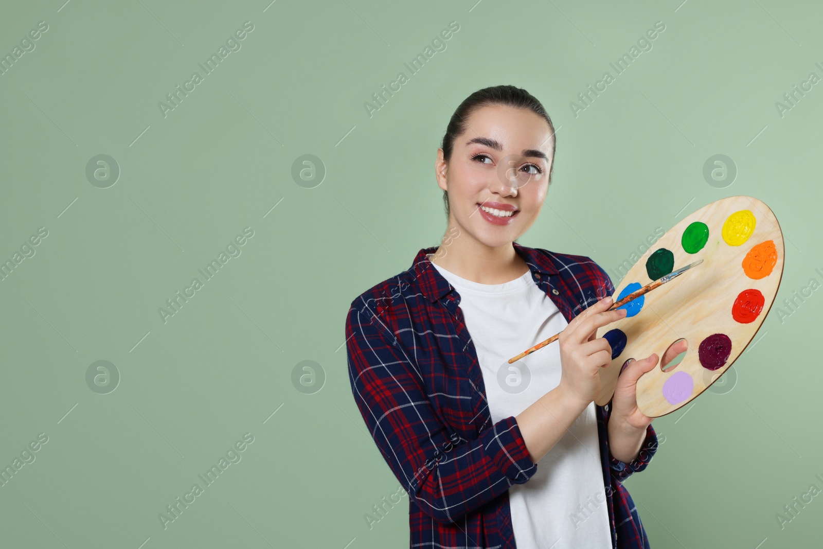 Photo of Woman with painting tools on pale green background, space for text. Young artist