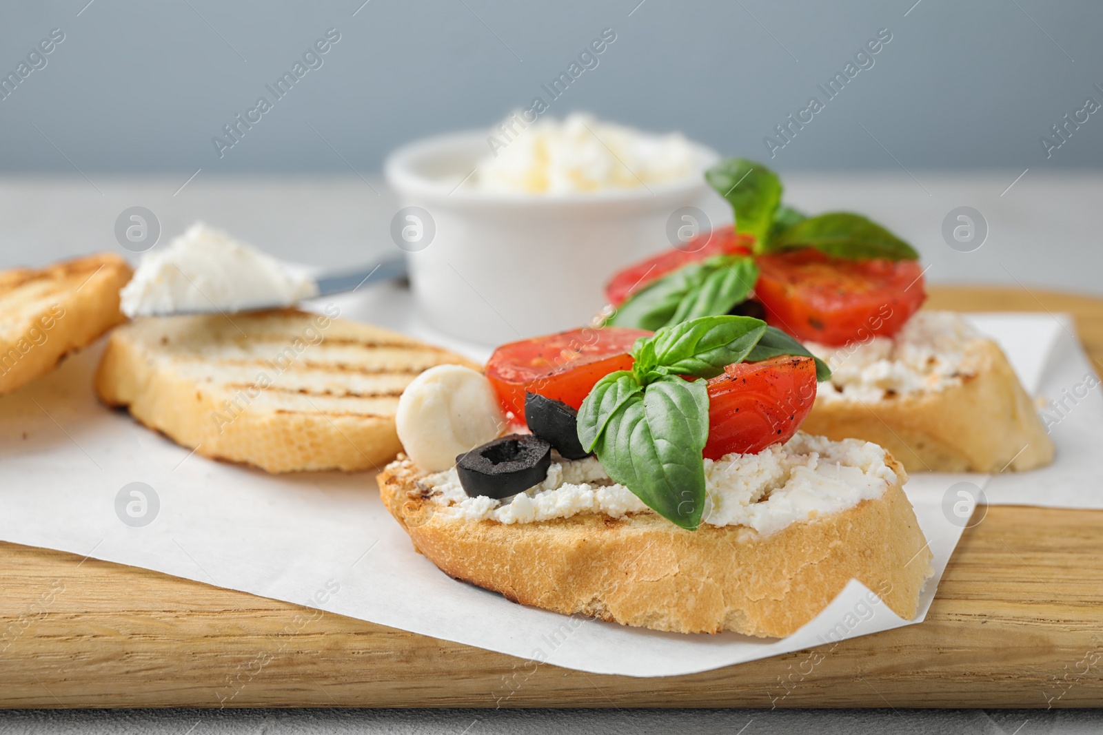 Photo of Wooden board with delicious tomato bruschettas on table, closeup