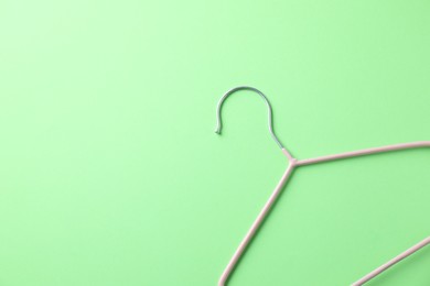 Photo of One pink hanger on light green background, top view. Space for text