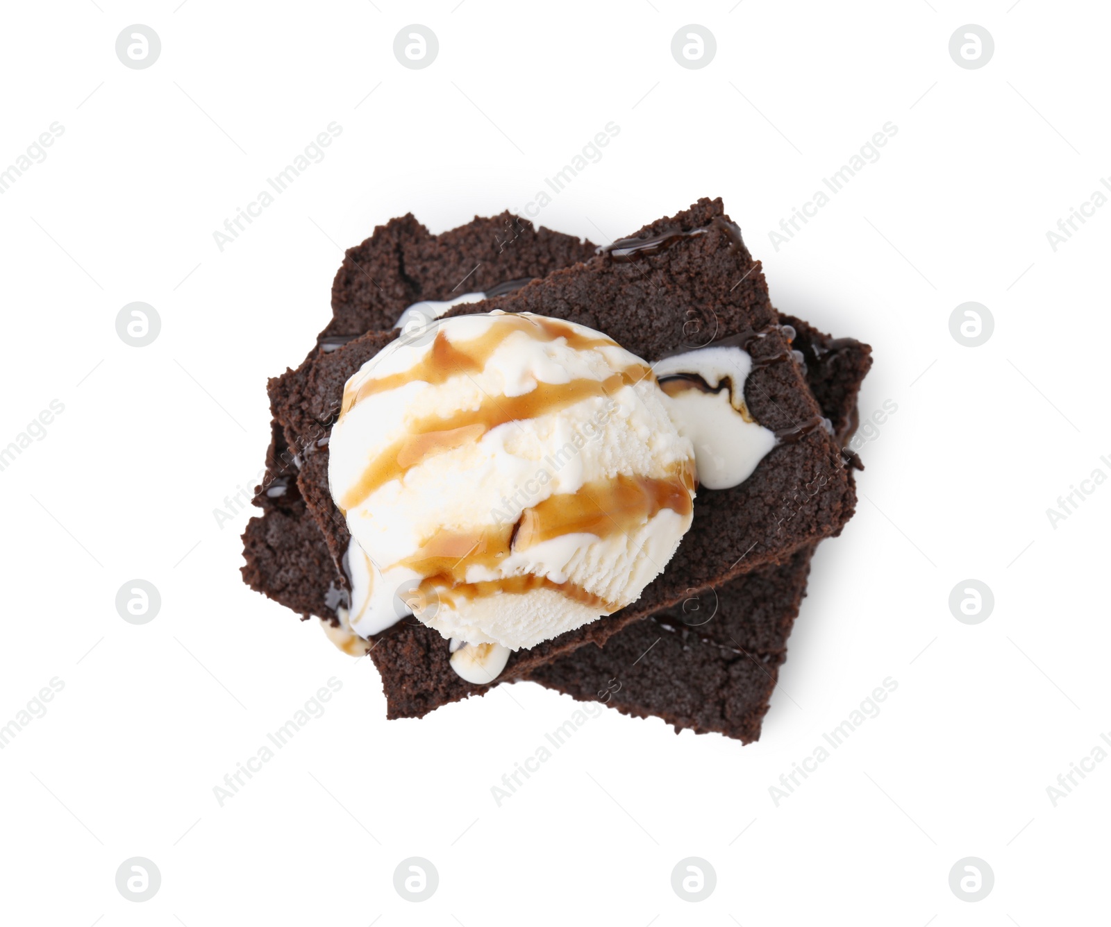 Photo of Tasty brownies with ice cream and caramel sauce isolated on white, top view