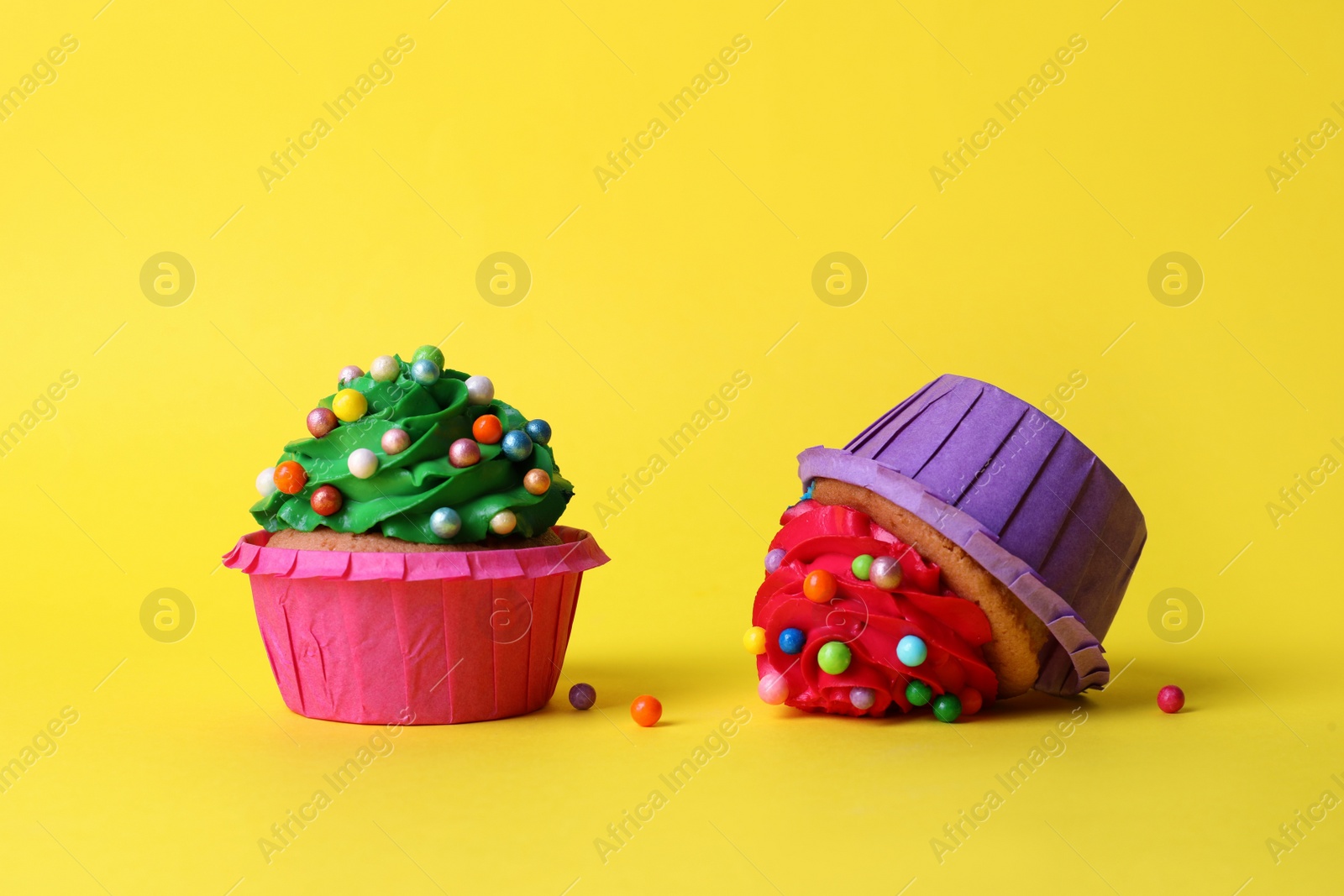 Photo of Dropped and good cupcakes on yellow background. Troubles happen