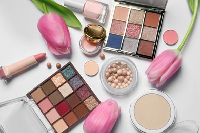 Photo of Flat lay composition with eyeshadow palettes and beautiful flowers on white background