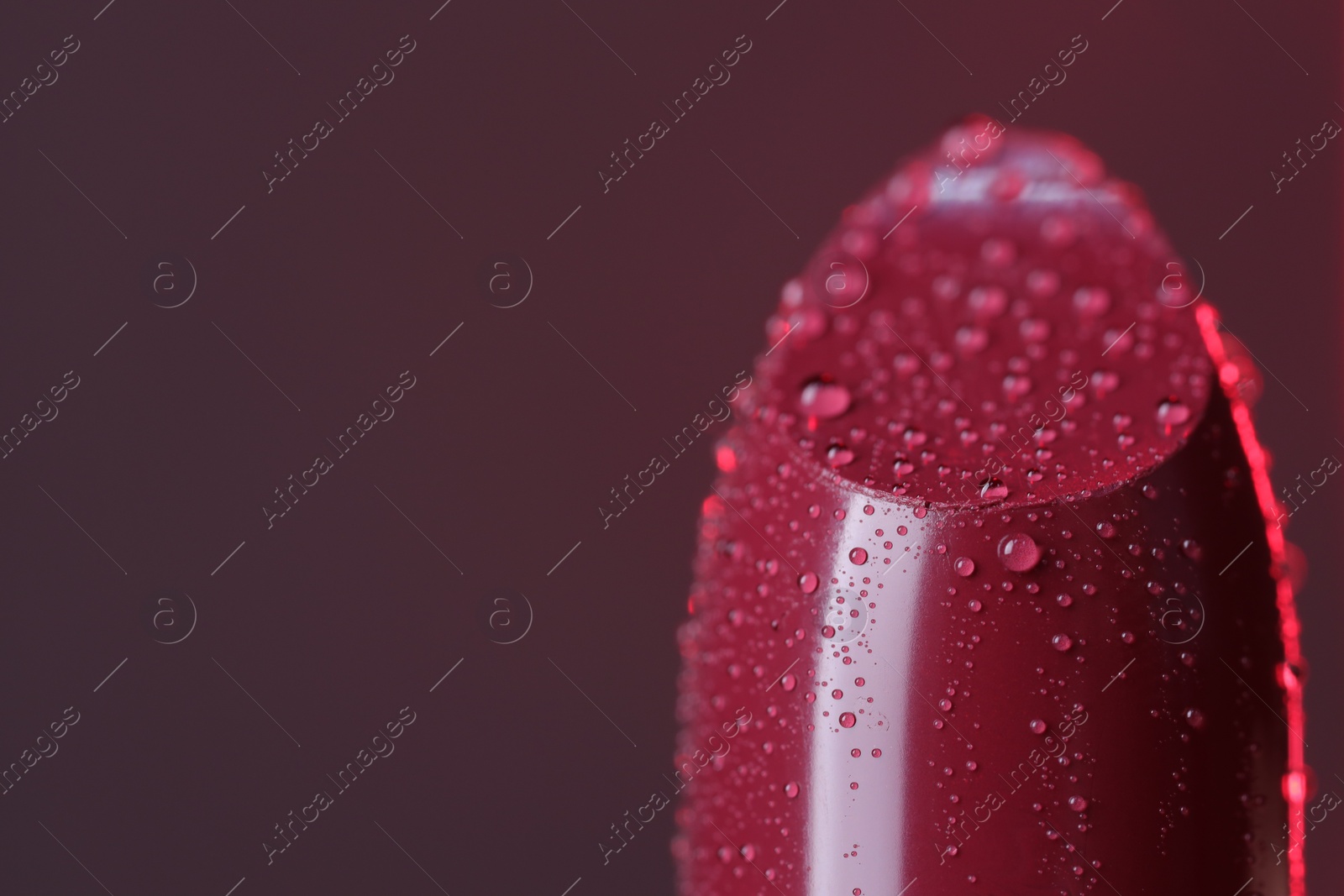 Photo of Beautiful red lipstick with water drops on brown background, macro view. Space for text