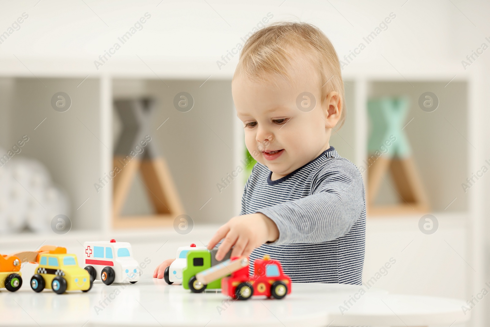 Photo of Children toys. Cute little boy playing with toy cars at white table in room, space for text