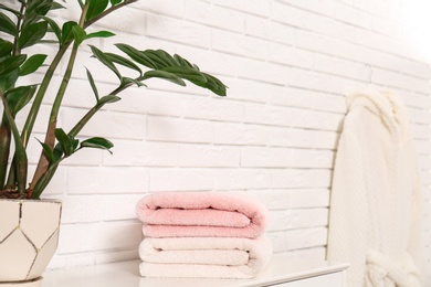 Photo of Clean folded towels on table near brick wall. Space for text