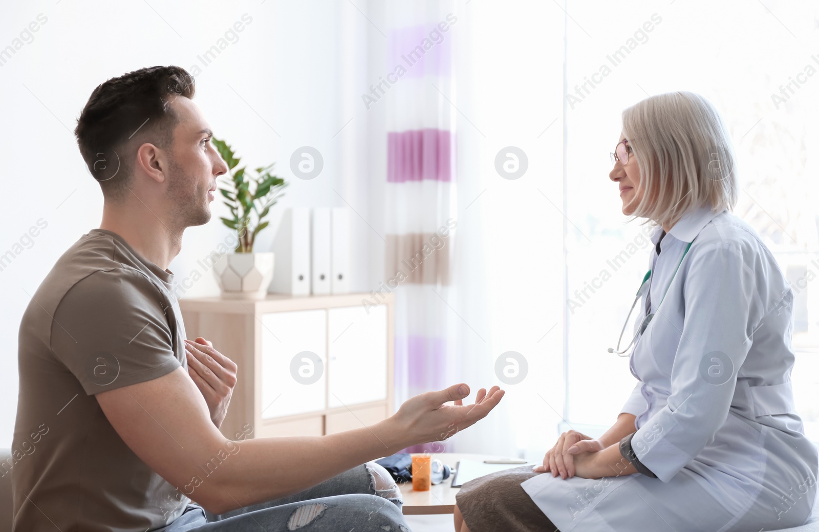 Photo of Mature doctor consulting patient at home