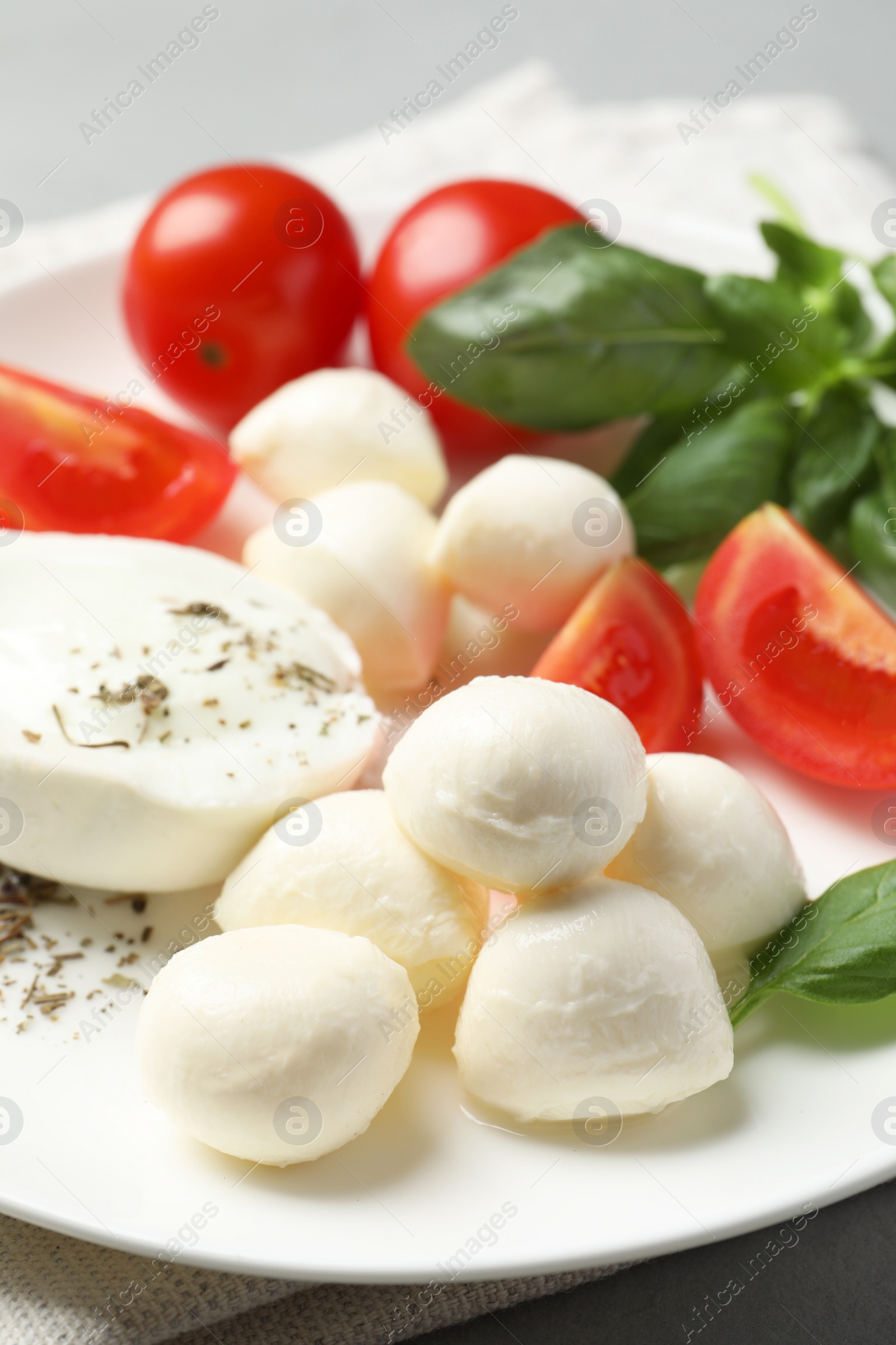 Photo of Delicious mozzarella with tomatoes and basil leaves on table, closeup