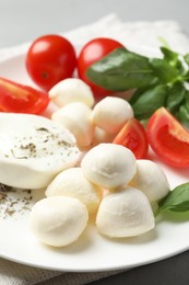 Photo of Delicious mozzarella with tomatoes and basil leaves on table, closeup