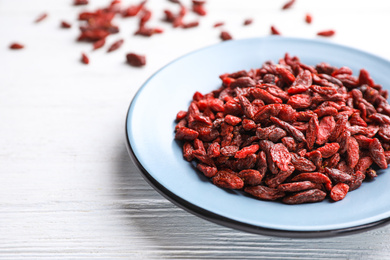 Photo of Dry goji berries on white wooden table, closeup