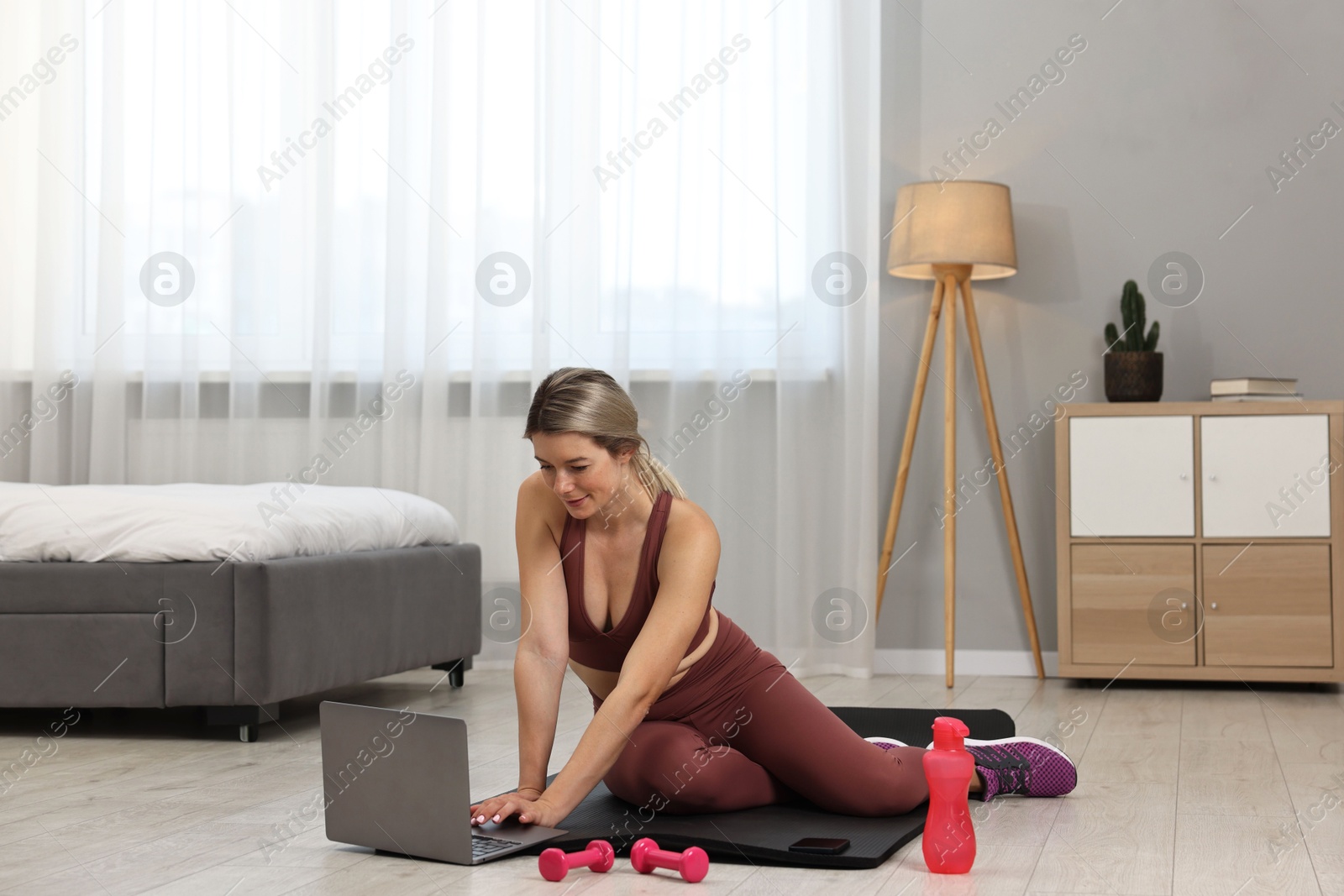 Photo of Online fitness trainer. Woman watching tutorial on laptop at home