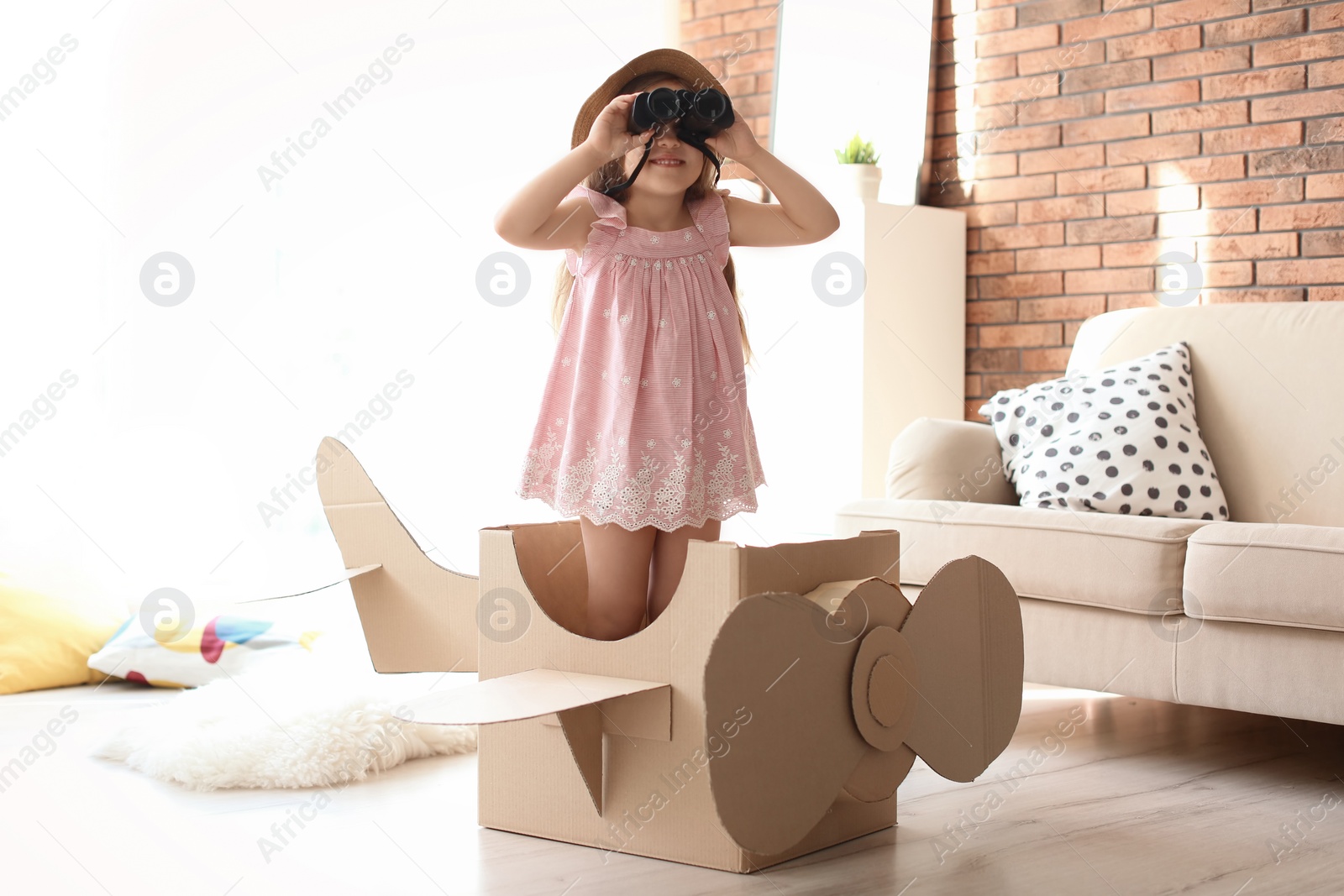 Photo of Adorable little child playing with cardboard plane at home