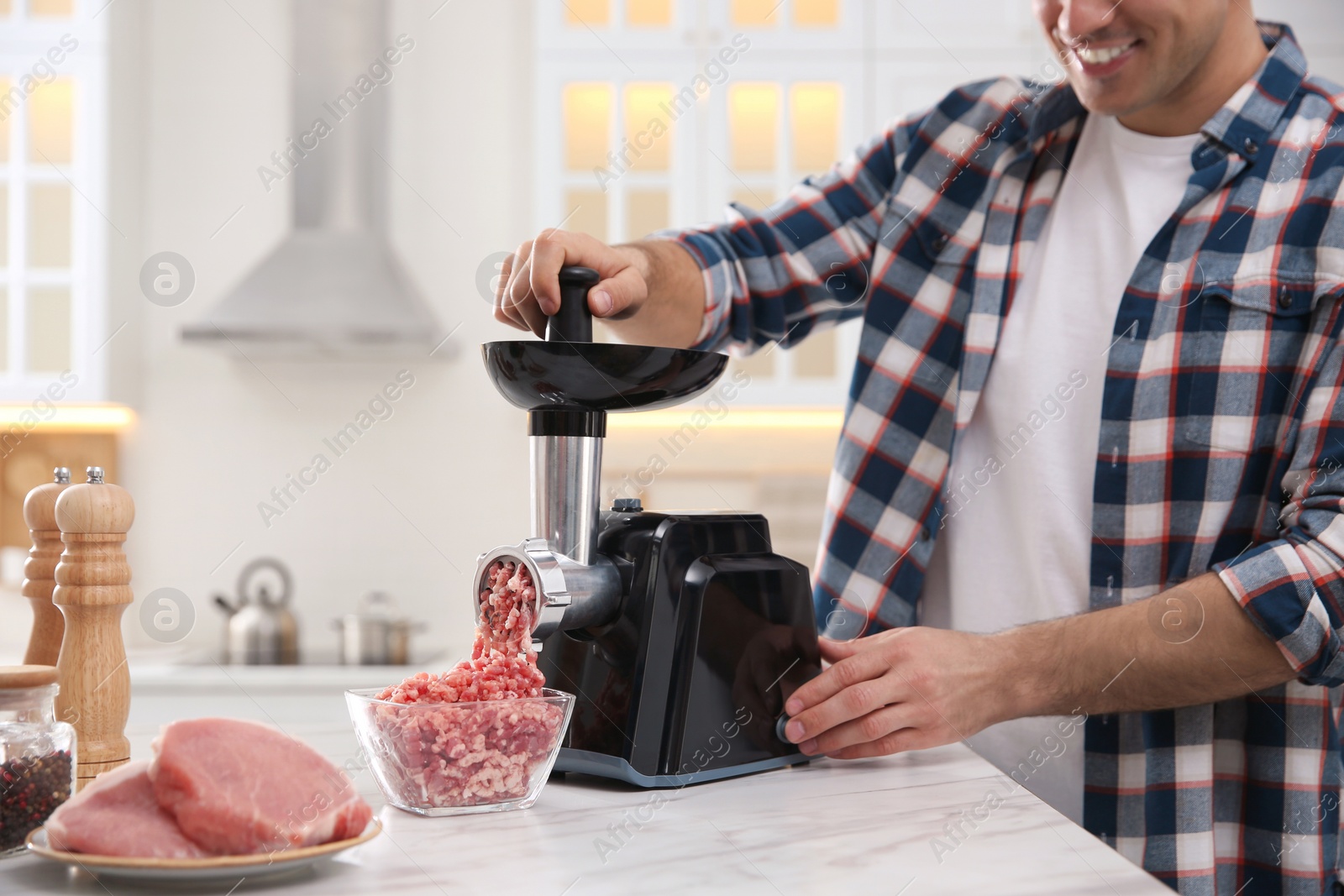 Photo of Man using modern meat grinder in kitchen, closeup