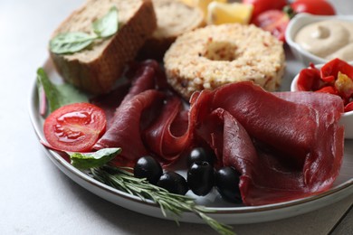 Photo of Delicious bresaola and other ingredients for sandwich on light grey table, closeup