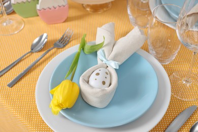 Festive table setting with painted egg, plate and tulip flower. Easter celebration