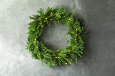 Photo of Beautiful Christmas wreath with festive lights on grey wall