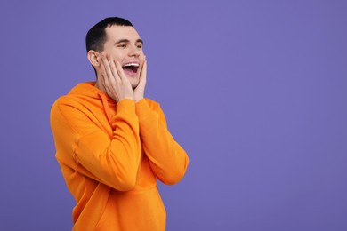 Portrait of surprised man on purple background, space for text