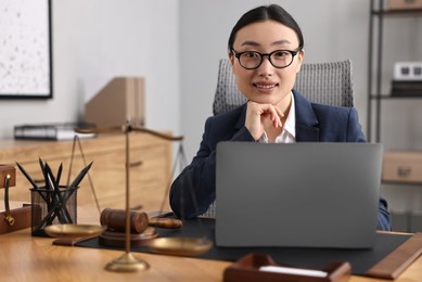 Photo of Portrait of smiling notary working with laptop at table in office