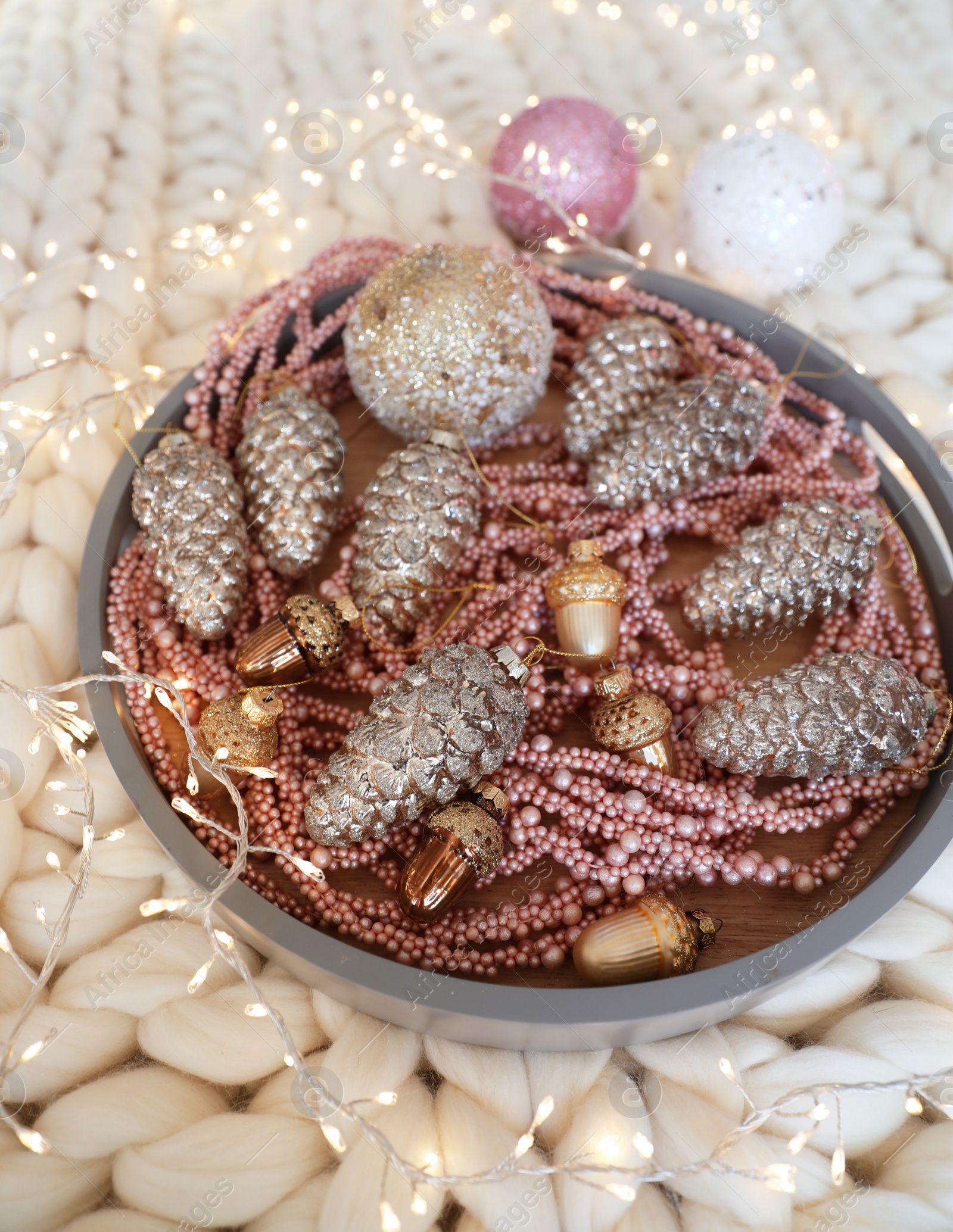 Photo of Beautiful Christmas tree baubles and fairy lights on white knitted fabric