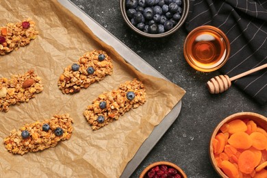 Making granola bars. Baking tray and ingredients on grey table, flat lay