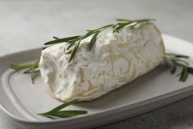 Photo of Delicious fresh goat cheese with rosemary on light grey table, closeup