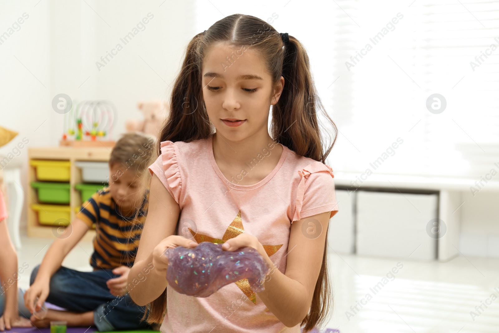 Photo of Preteen girl playing with slime in room