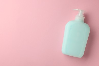 Photo of Bottle of liquid soap on pink background, top view. Space for text