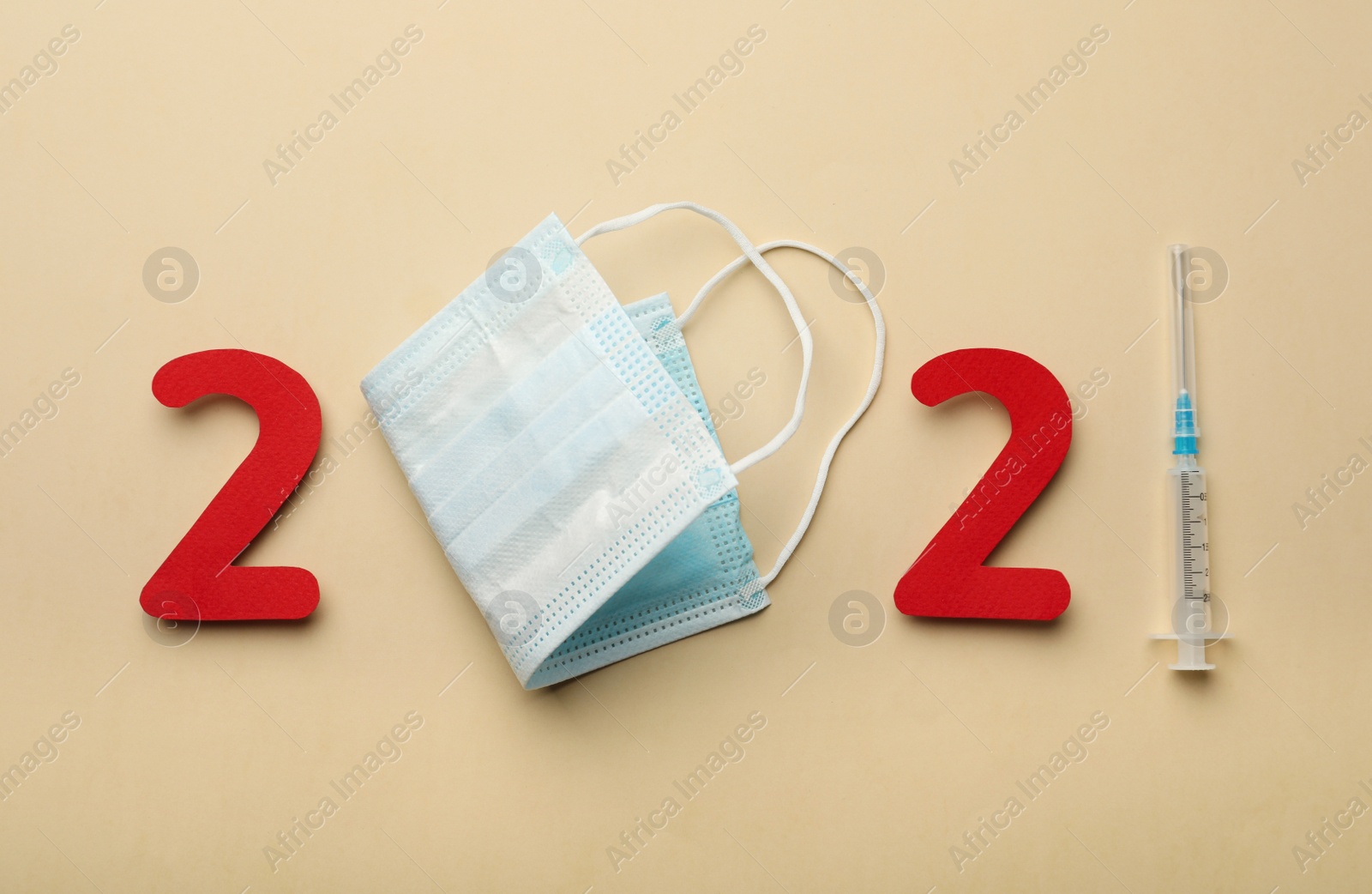 Photo of Paper numbers, medical mask and syringe forming 2021 on beige background, flat lay. Coronavirus vaccination