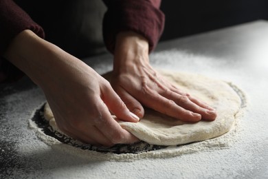 Woman kneading pizza dough at table, closeup