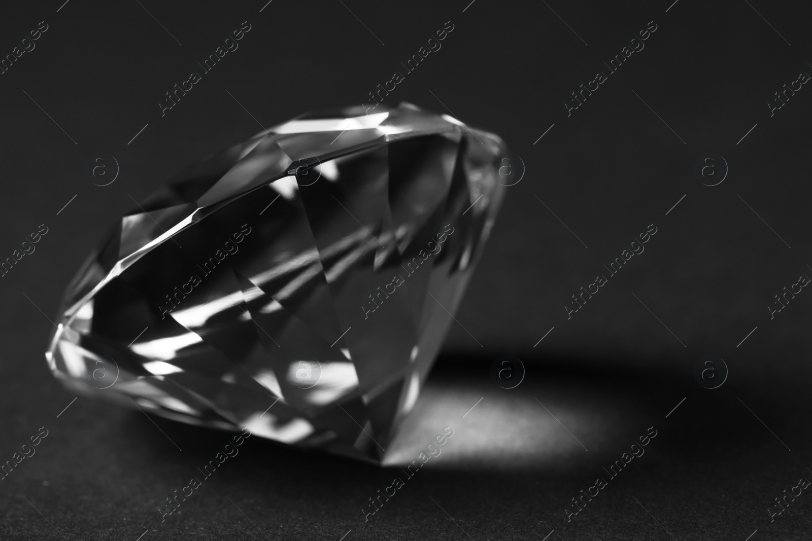 Photo of Beautiful dazzling diamond on dark background, closeup. Space for text