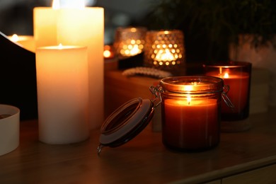 Lit candles on wooden table in dark room