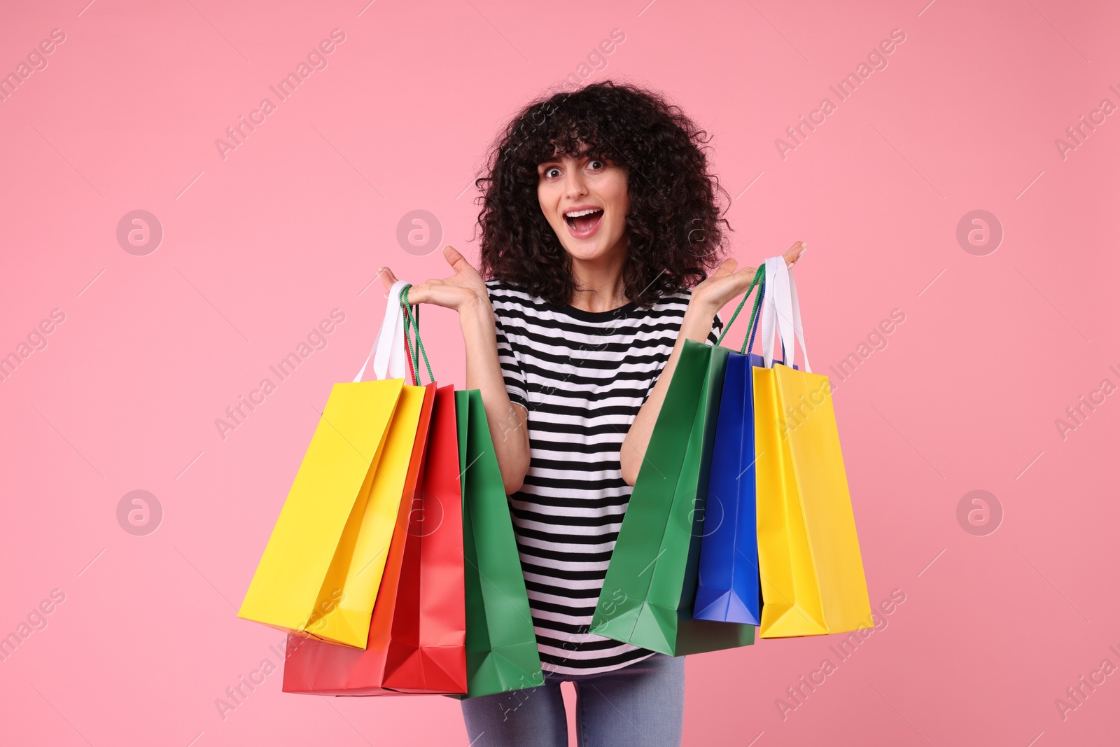 Photo of Happy young woman with shopping bags on pink background