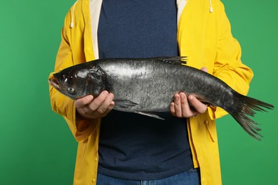 Photo of Fisherman with caught fish on green background, closeup