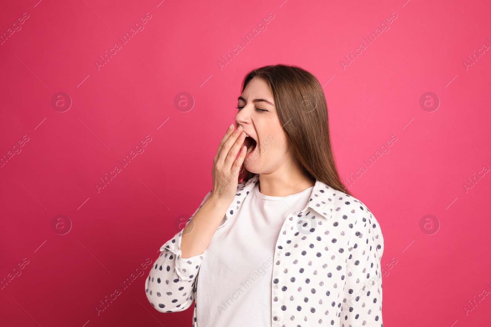 Photo of Young tired woman yawning on pink background