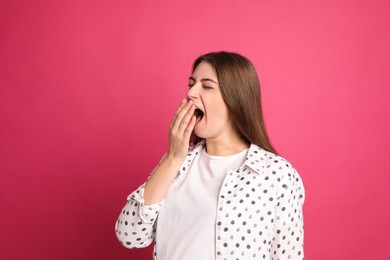 Photo of Young tired woman yawning on pink background