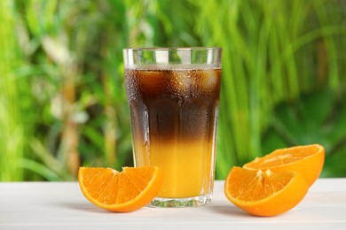 Photo of Tasty refreshing drink with coffee and orange juice on white table against blurred background