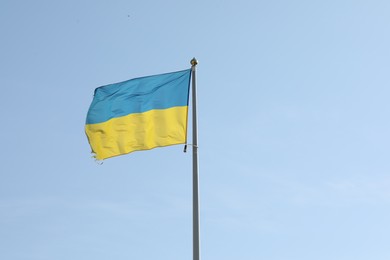 Flag of Ukraine waving on pole against blue sky