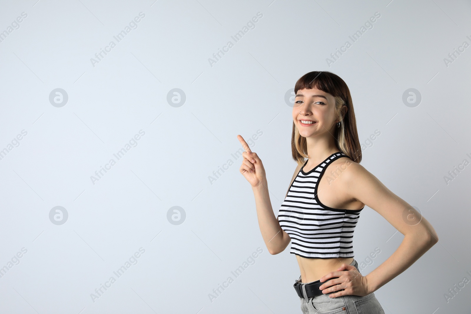 Photo of Beautiful young girl pointing on white background. Space for text