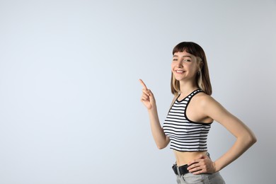 Photo of Beautiful young girl pointing on white background. Space for text