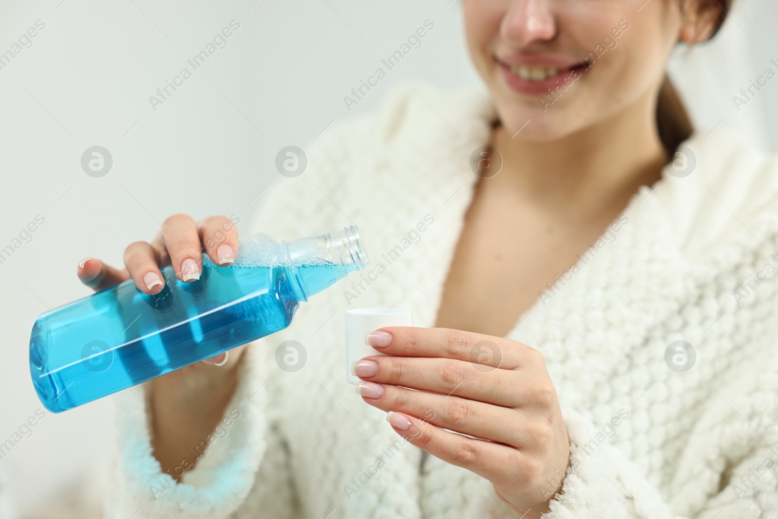 Photo of Young woman using mouthwash on light background, closeup