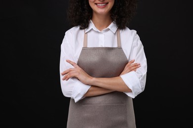 Woman wearing kitchen apron on black background, closeup. Mockup for design