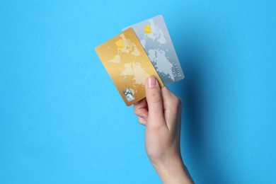 Photo of Woman holding credit cards on light blue background, closeup